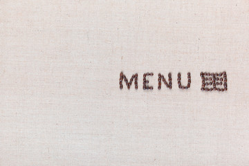 Menu word with icon made from roasted coffee beans on linen creamy linen canvas, shot from above, aligned middle right.