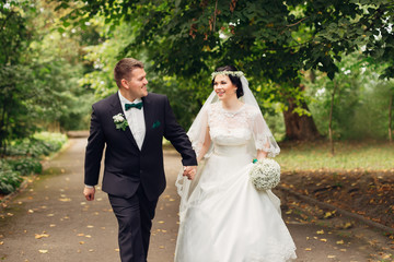 newlyweds are walking in the park and looking at each other. The
