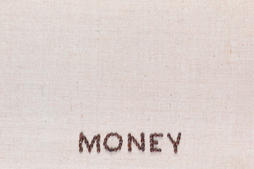 Money written with coffee beans on linen texture, arranged bottom center.