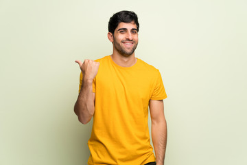 Young man over pink wall pointing to the side to present a product