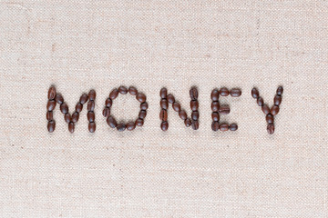 Money written with coffee beans on linen texture, shot close up.