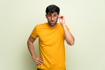 Young man over pink wall with glasses and surprised