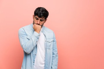 Young man over pink wall having doubts