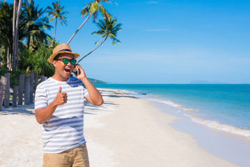 Young asian man on the beach using smartphone.