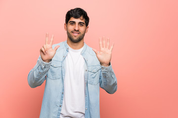 Naklejka premium Young man over pink wall counting eight with fingers