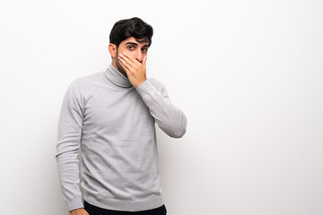 Young man over isolated white wall covering mouth with hands