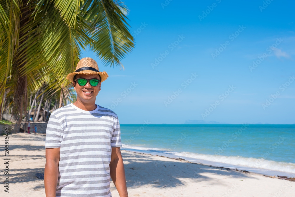 Wall mural happy young asian man on beach in vacation time.