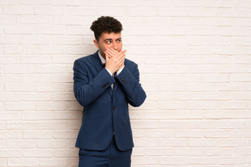 Man in suit and bow tie covering mouth and looking to the side