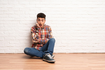 Fototapeta na wymiar Young man sitting on the floor surprised and shocked while looking right