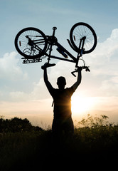 Concept of an active lifestyle. Cycling. Silhouette of cyclist with arms raised up to the sky