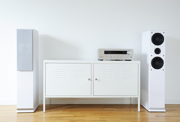 Modern audio stereo system with white speakers on bureau in modern interior