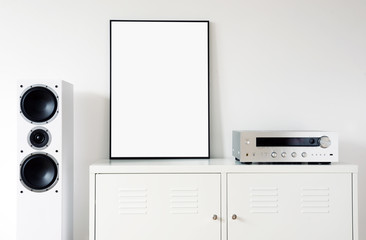 Poster on table in room.Modern audio stereo system with white speakers on bureau in modern interior	