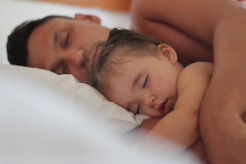 Dad hugs his daughter in a dream. A man and a child sleeping on white pillow