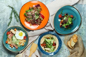 Multi-colored plates with different salads. Beautiful serving of dishes. Light gray background. Restaurant menu