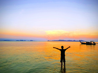 happy fresh morning sunrise with amazing luxury horizon , beautiful color of sea and young man slowly exercising for good health, near fishing boat at Koh Kradan Island, South of Thailand.Andaman