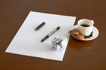 Closeup of wood desktop with blank sheet of paper, pen, and other items