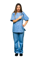Full body of Young nurse surprised and pointing side