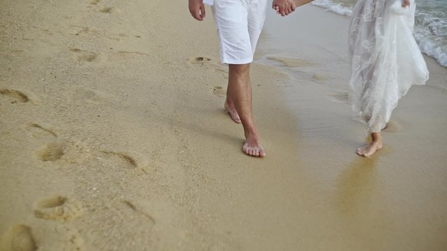 Couple of lovers walking on the each at sunset - Foot prints on the beach - slow motion