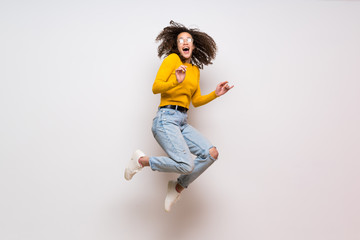 Dominican woman with curly hair jumping over isolated white background