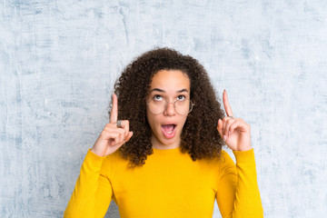 Dominican woman over isolated green background pointing with the index finger a great idea