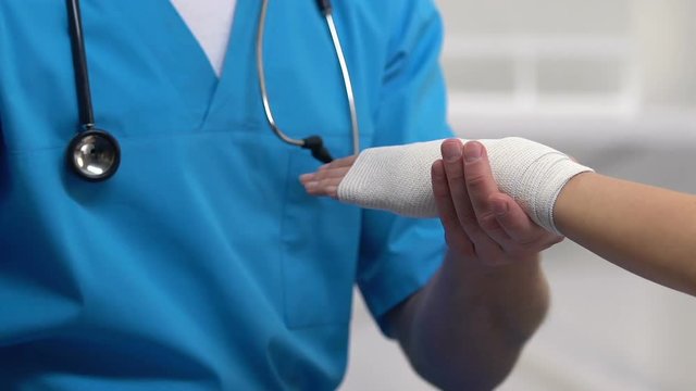 Therapist applying wrist elastic wrap to female patient, sport sprain problem