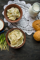Dumplings with potatoes and cabbage. Sour cream, milk and greens. Traditional dish of Ukraine. Dark wooden background.