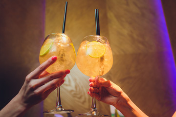 women raising a glasses of aperol spritz at the dinner table.