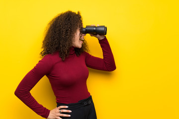 Dominican woman with turtleneck sweater and looking in the distance with binoculars