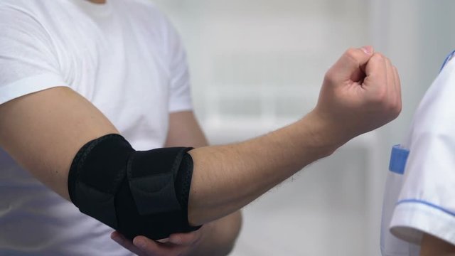 Female doctor applying elbow padded orthosis, decrease arthritis pain symptoms