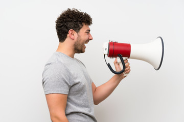 Man with curly hair over isolated wall shouting through a megaphone