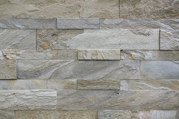 Natural stone, smooth linear masonry, gray relief texture. The wall is made of stone, the surface is textured, yellow color.
