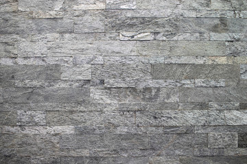 Natural stone, smooth linear masonry, gray relief texture. The wall is made of stone, the surface is textured, gray.