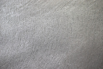 Gray textured plaster on the wall is embossed. The texture on the wall is rough without seams.