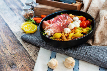 Salad made with cooked pasta, mixed green salads, cherry tomatoes, Mozzarella cheese and smoked ham served with accompaniment