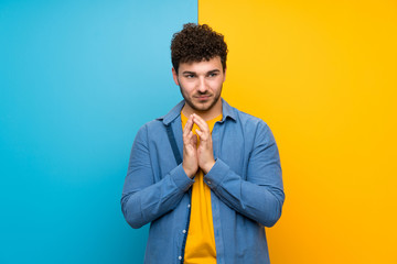 Man with curly hair over colorful wall scheming something