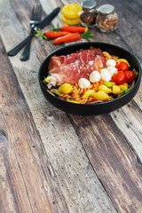Salad made with cooked pasta, mixed green salads, cherry tomatoes, Mozzarella cheese and smoked ham served with accompaniment