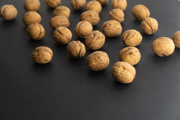 Walnuts in shell lying on black surface, side view. Healthy nuts and seeds background.