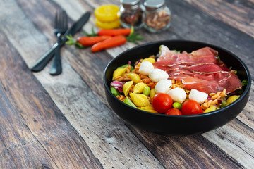 Salad made with cooked pasta, mixed green salads, cherry tomatoes, Mozzarella cheese and smoked ham served with accompaniment
