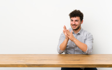 Young man with a table applauding after presentation in a conference