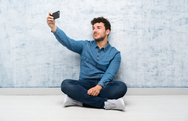 Young man sitting on the floor making selfie with cellphone