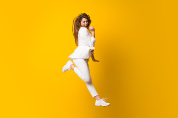 Young woman jumping over isolated yellow wall