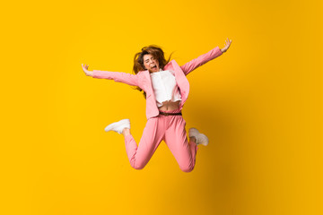 Fototapeta na wymiar Young woman jumping over isolated yellow wall making victory gesture