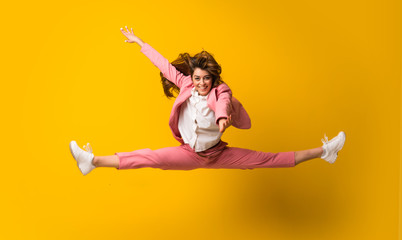 Young woman jumping over isolated yellow wall