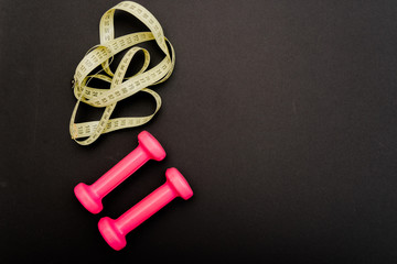 Fototapeta na wymiar pink dumbbells a healthy lifestyle for a beautiful body to lose weight and have a sports figure to cultivate the right eating habits and diet on a black background