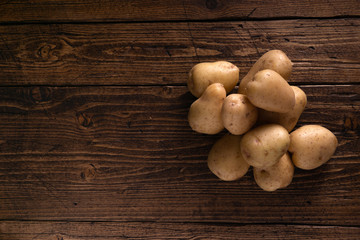 Heap of fresh clean potatoes on rustic wooden surface. Organic food, carbs, tubers.