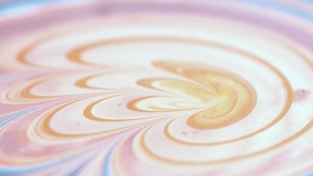 Artist creates absractive ebru design with orange, pink and white paints