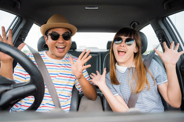 Front view of Funny moment couple asian man and woman sitting in car. Enjoying travel concept.