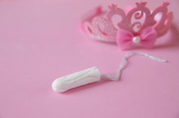 Clean white cotton tampons on pink background with a crown in the background in soft blur. Menstruation. Feminine Hygiene in periods, beauty treatment.
