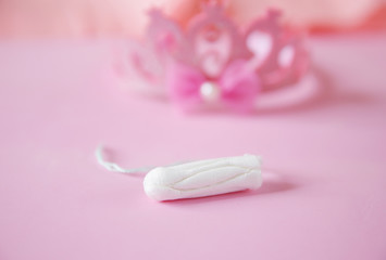 Fototapeta na wymiar Clean white cotton tampons on pink background with a crown in the background in soft blur. Menstruation. Feminine Hygiene in periods, beauty treatment.