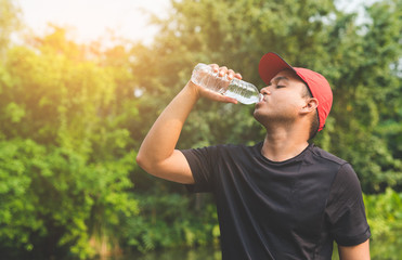 Young fitness man runner  drinking bottle of water.